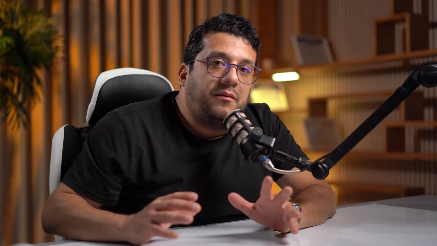 Intervenant assis à un bureau, face caméra, micro sur bras articulé